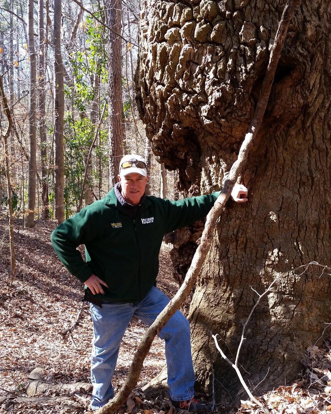 Darrell standing in winter woods beside a huge old tree with a large burl on its trunk