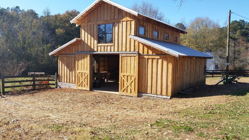 A board-and-batten barn with a raised loft, metal roof and open sliding doors